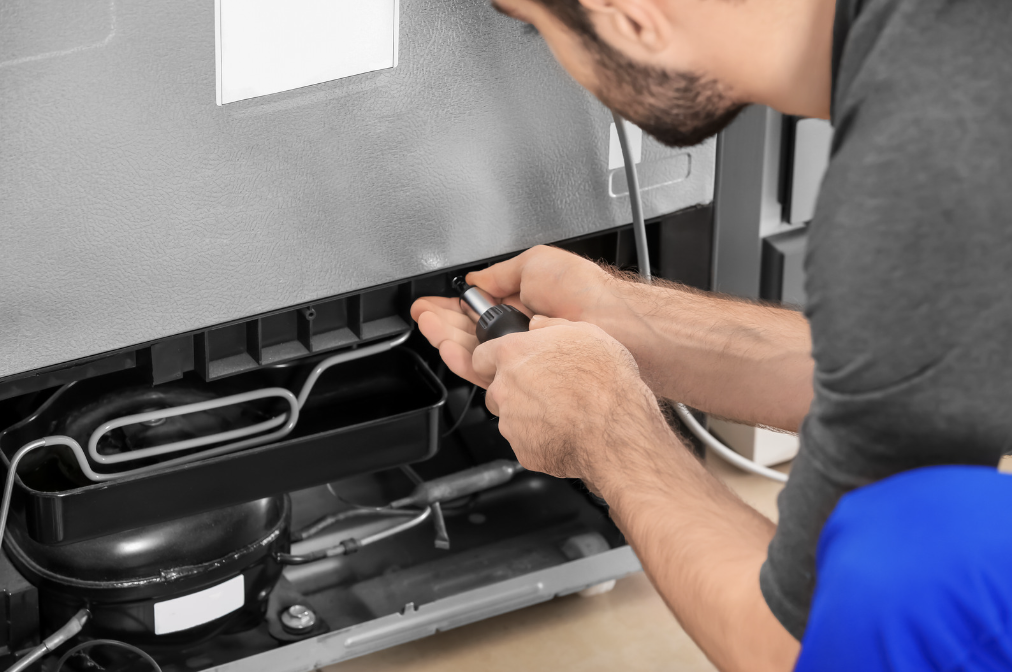 Man working on a refrigerator with a screwdriver